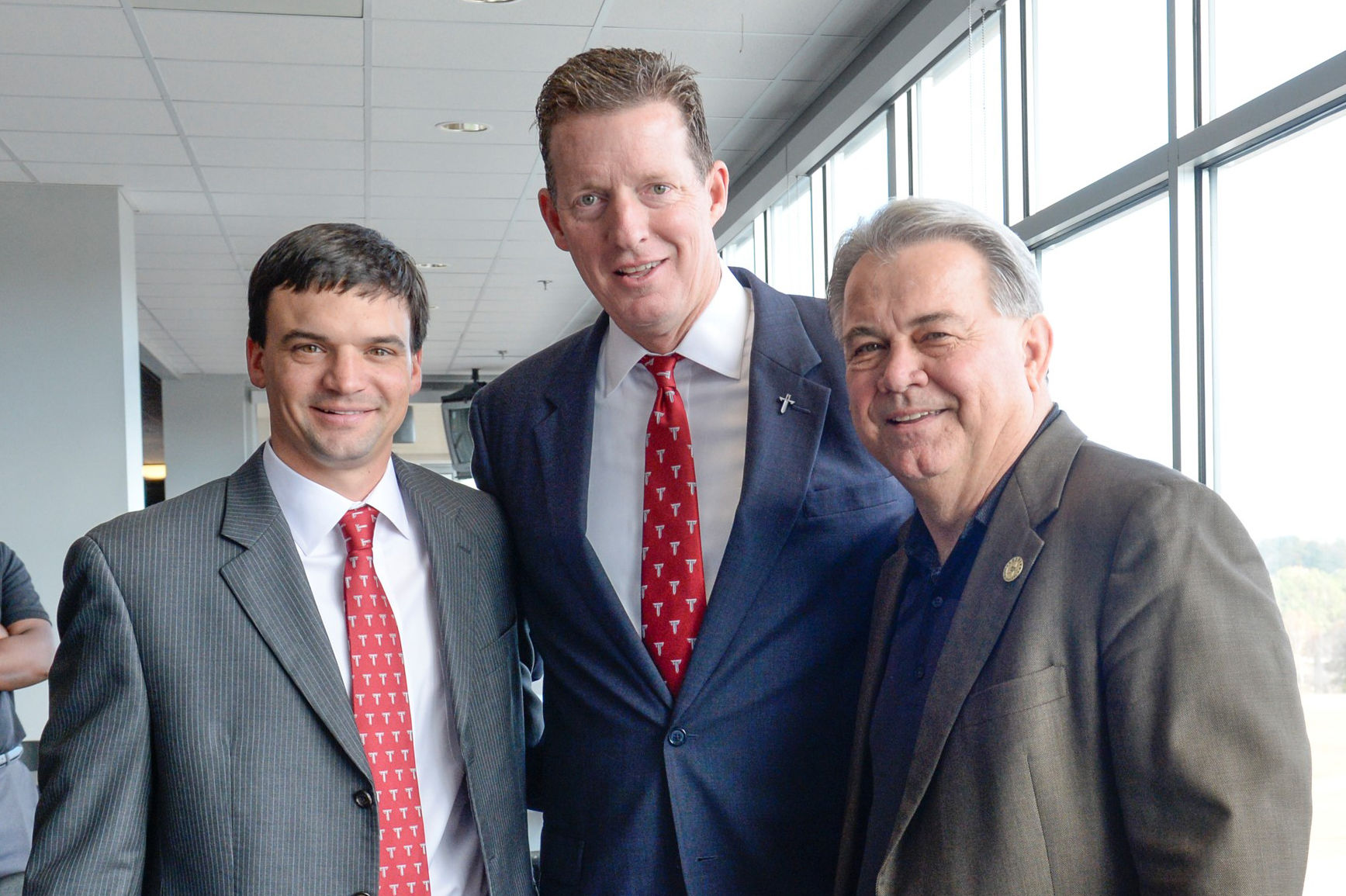 Brown (left) pictured alongside then-athletic director John Hartwell (center) and out-going head coach Larry Blakeney on the day Brown was introduced as Troy's new head coach.